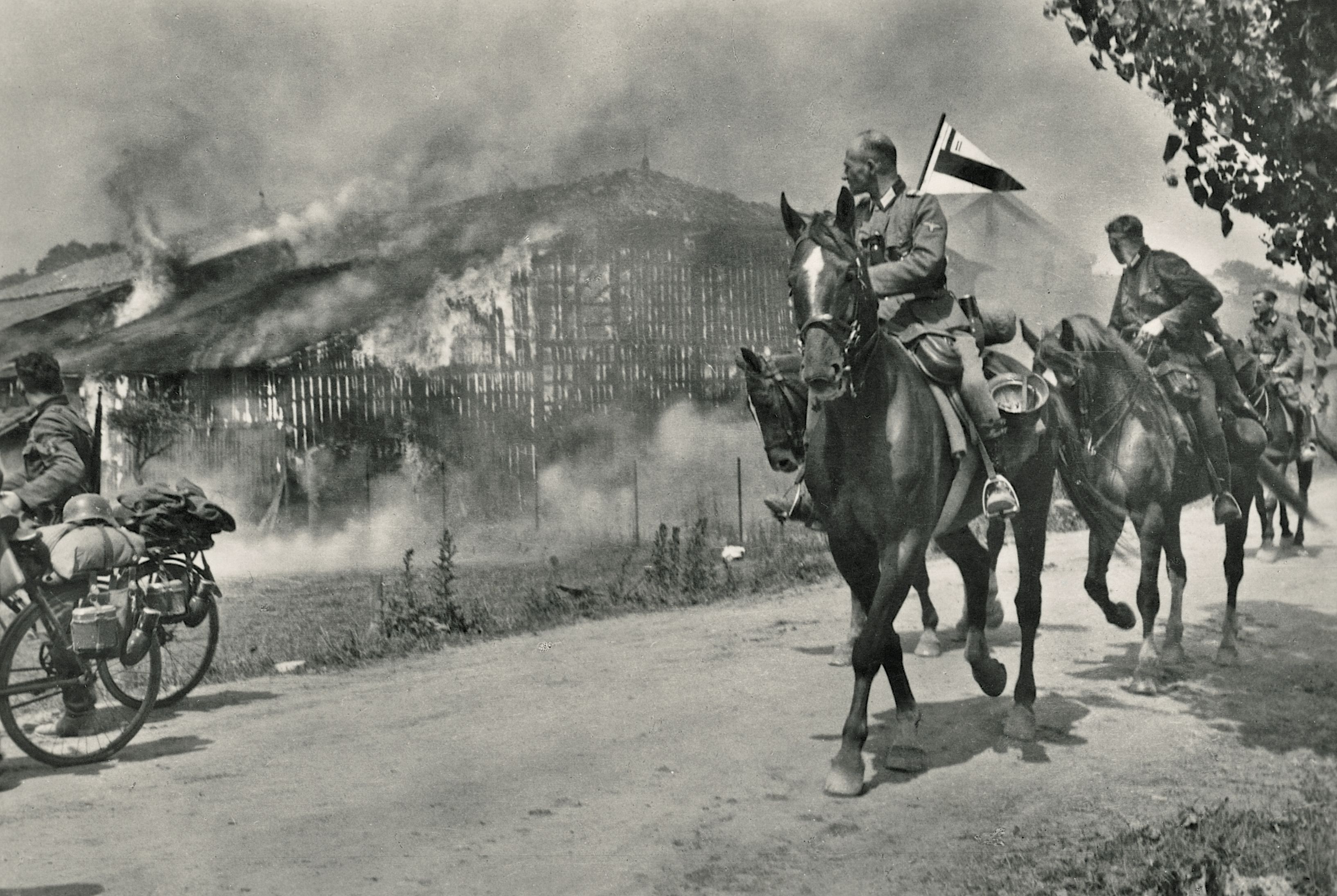 German SS and police troops in Russia ride past a burning structure as they pillage captured territory. Nazi Germany made it official policy to starve Russians, kill them on sight or exterminate them through forced labor. Devyatayev, 27, was made a slave laborer after being captured. / Museum of Danish Resistance Archive