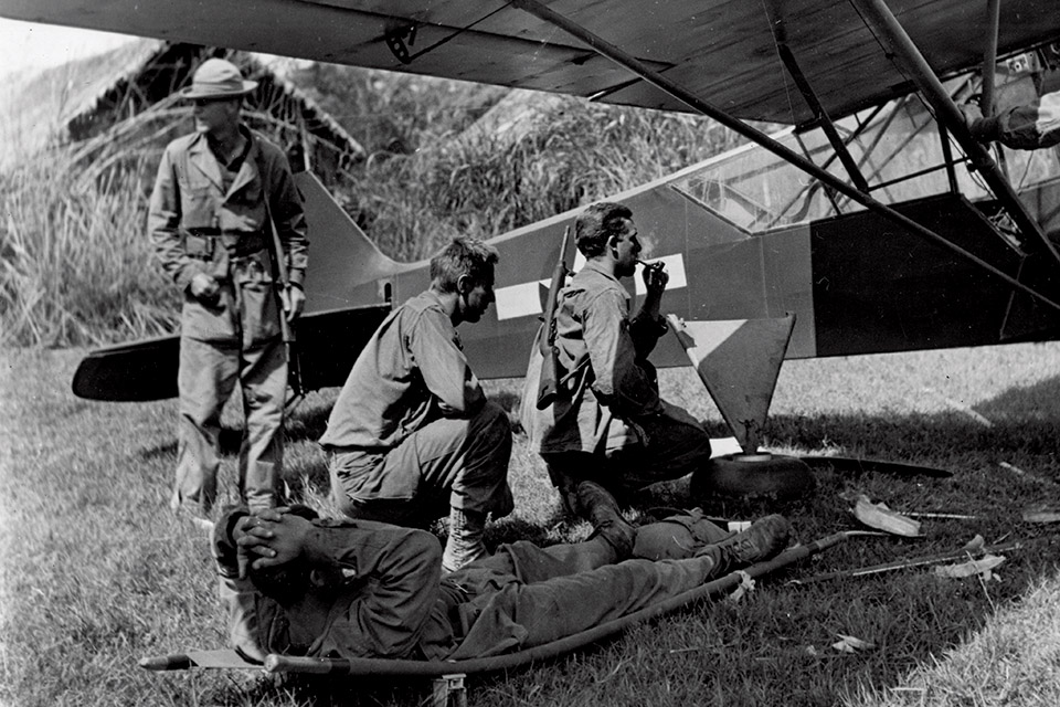 Members of Merrill's Marauders load a wounded soldier into an L-4 Grasshopper. (National Archives)