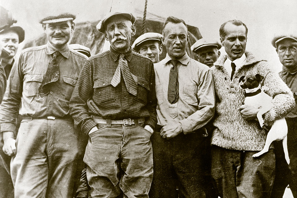 Norge’s crew assembles after their transpolar flight. From left in the foreground are Lars Riiser-Larsen, Amundsen, Lincoln Ellsworth and Umberto Nobile, holding his terrier Titina. (National Library of Norway)
