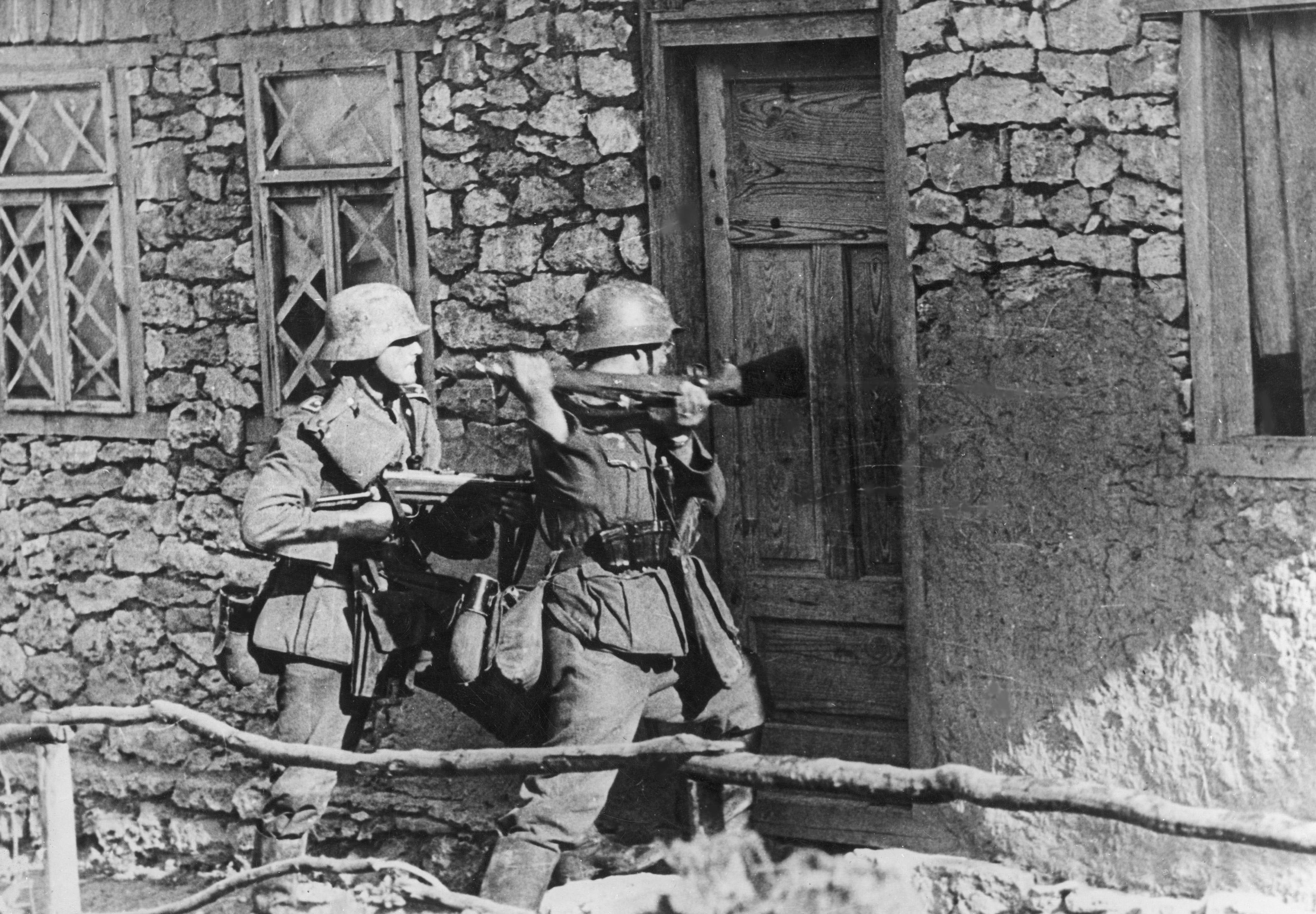 German soldiers attempt to break into a building on the Eastern Front c. 1941. Similarly to the soldier in this photo, German troops reaching the Catherine Palace in September 1941 used rifle butts to smash pieces from the walls of the Amber Room. / Polish State Archive