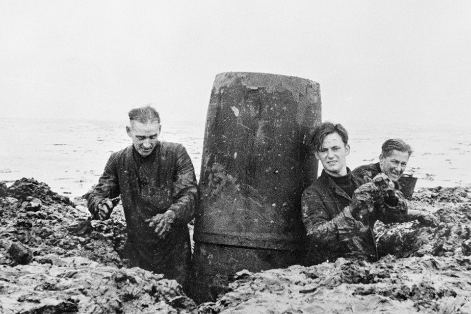A clearance team recovers a German magnetic mine from the British shore. (AWM P05468.013)