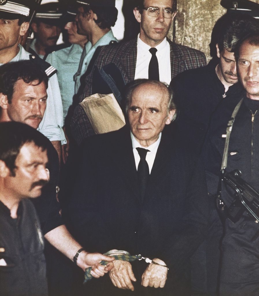A handcuffed Klaus Barbie is led by policemen in Lyon, after he was convicted on July 4, 1987, of crimes against humanity and sentenced to life in prison. Barbie was known as the “Butcher of Lyon” for his brutal actions as Gestapo chief in this city. (AP Photo/Laurent Rebours)