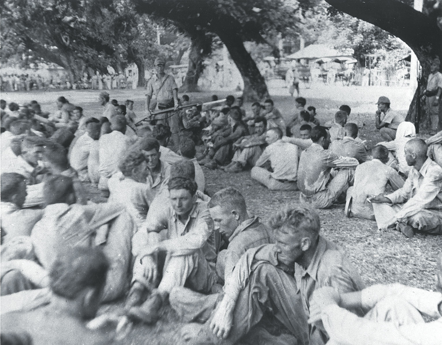 American prisoners of war sit under Japanese guard before the start of the Bataan Death March. Yamashita evaded responsibility for the march. / U.S. Marine Corps