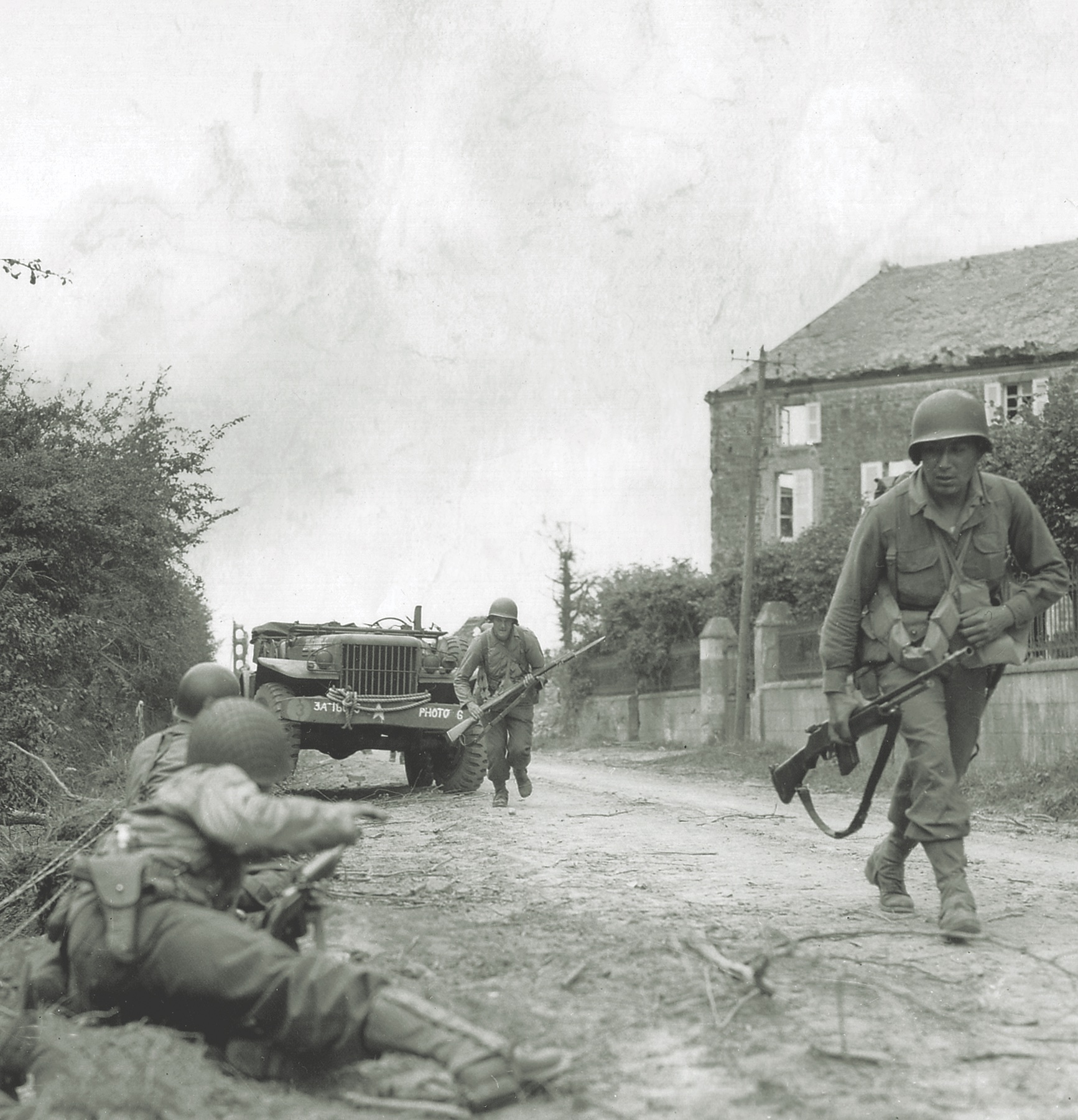 Soldiers of the 79th Division’s 314th Infantry Regiment reenact their assault on the German stronghold at La Haye-du-Puits, France, for an army photographer. (National Archives)