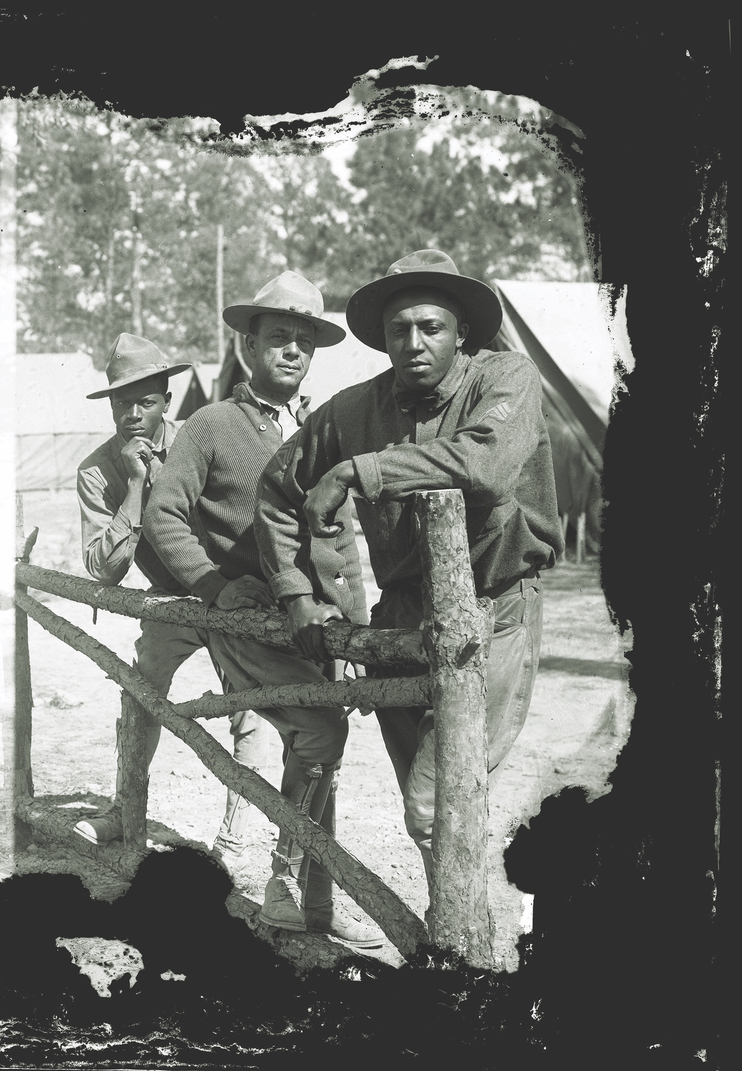 Three African American soldiers pose against a fence inside the camp. (Houston Public Library)