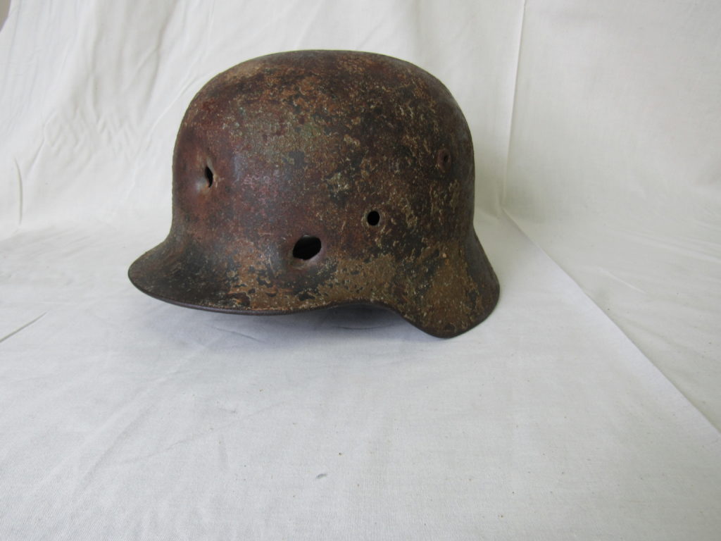 HOLES IN THE NARRATIVE: Found by an American soldier in a bunker on D-Day, this M-35 German helmet was kept as a souvenir for years before joining the National D-Day Memorial’s collection. The fate of its owner— presumably named “Wenz,” judging from a faded signature carved inside its brim—is unknown, but the bullet holes in its metal may provide some clues. 