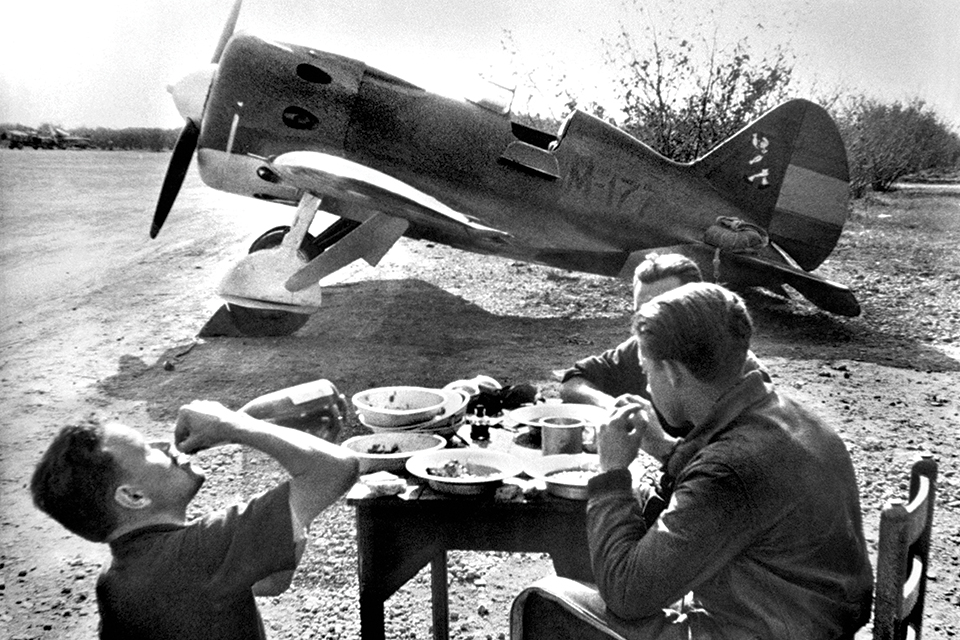 Republican pilots enjoy a meal between missions near a Polikarpov I-16 fighter. (©David Seymour/Magnum Photos)