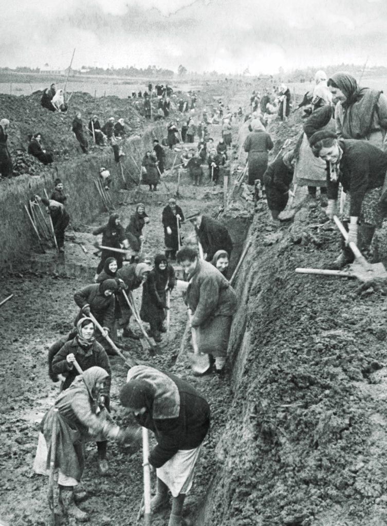 Soviet citizens, most of them women, dig an antitank ditch just outside Moscow (top). In case the Germans did reach the city, hundreds of factories were packed up and moved. Below, machinery from a railway car plant arrives at its new home in the Urals, 800 miles to the northeast. (Sovfoto/Universal Images Group via Getty Images)