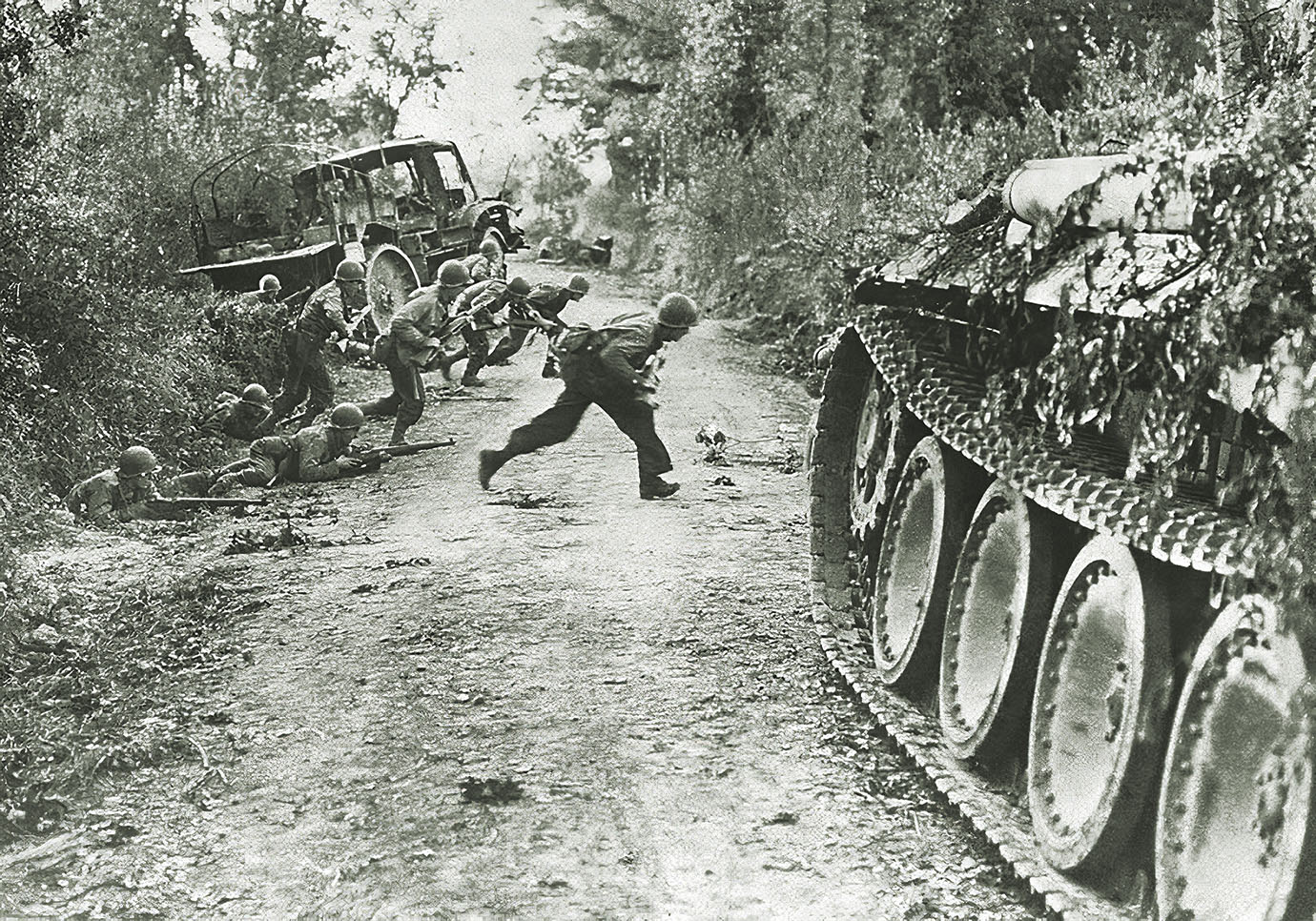 U.S. infantrymen dash across a farm road past a German tank and truck to the next hedgerow (below right). / Alamy