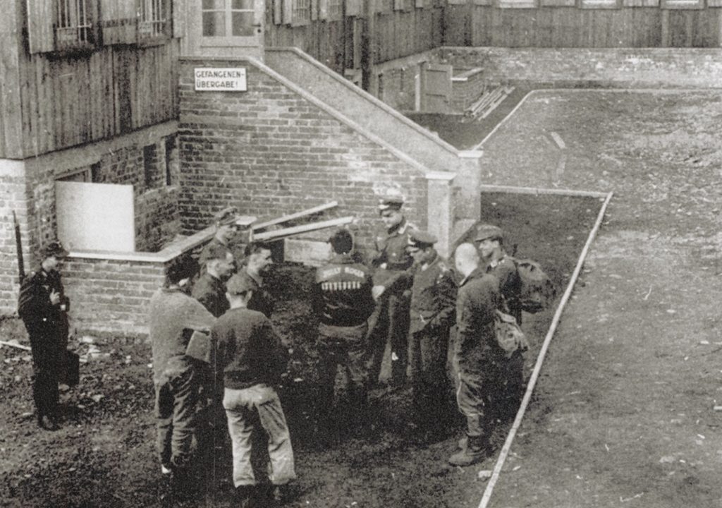 Surrounded by guards, captured Allied airmen await intake at the Luftwaffe interrogation center (above) outside Frankfurt. To encourage cooperation, they would be placed in solitary confinement cells; the painting below is by a B-24 navigator, Second Lieutenant Paul Canin. (Courtesy of Hanns-Claudius Scharff)