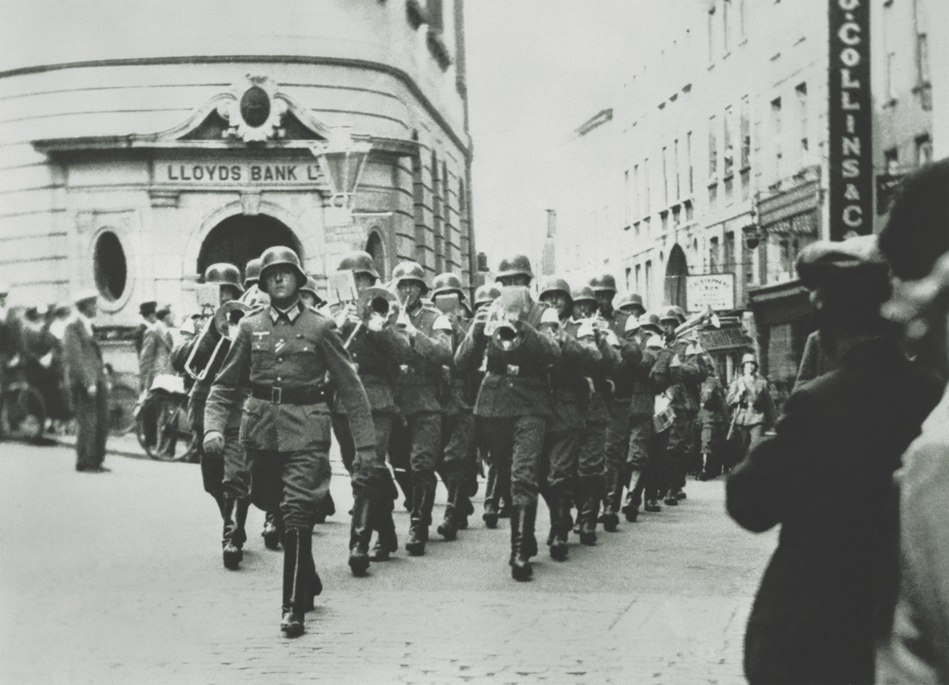 A German military band marchews past a branch of Lloyds Bank on The Pollet, one of the main streets in the capital of Saint Peter Port, Guernsey, during the Nazi occupation of the Channel Islands in World War II. (Imperial War Museums)