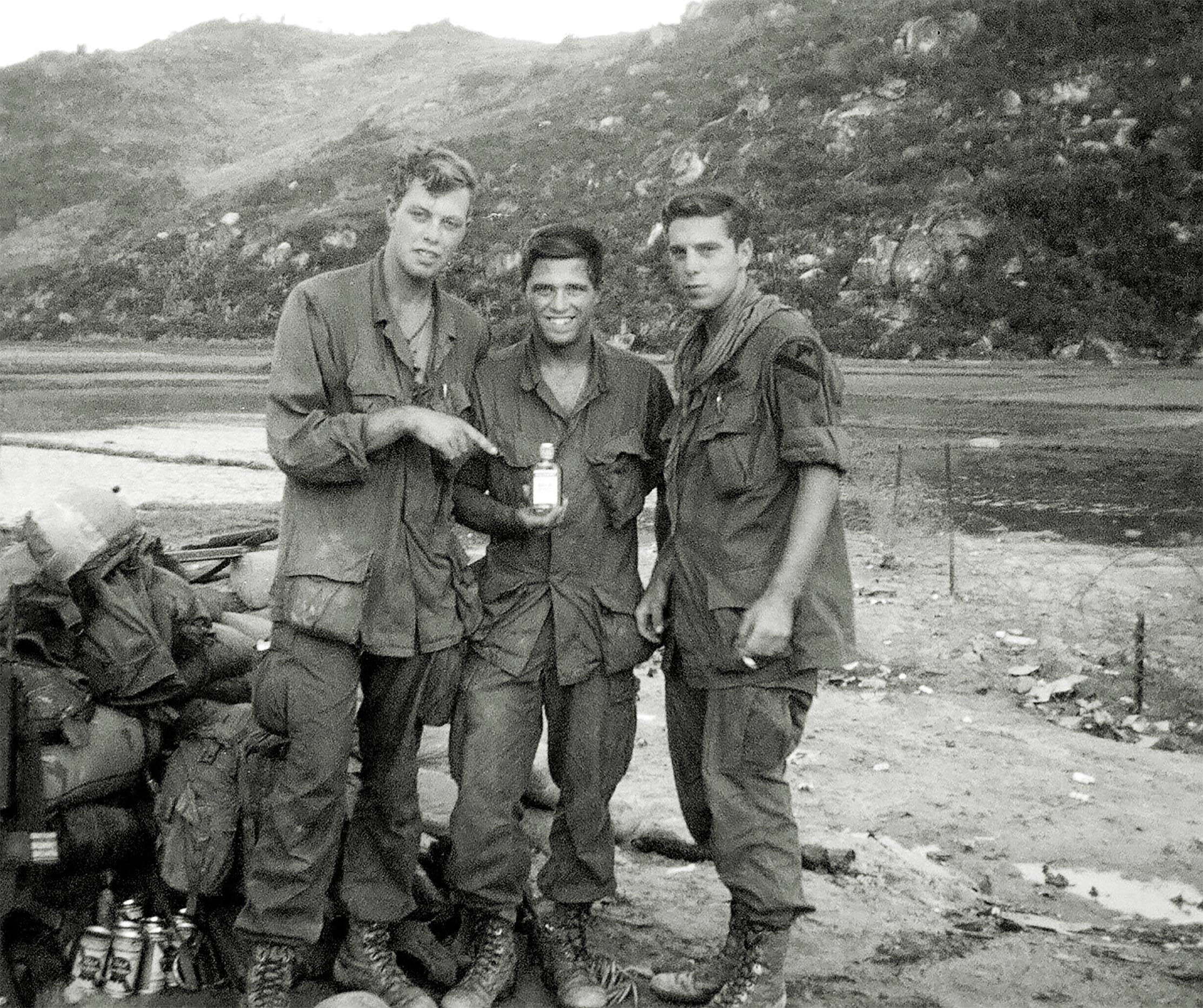 In his hunt for friends from the bar in Inwood, New York, Donohue found Rick Duggan, far left, of the 1st Cavalry Division (Airmobile), at Landing Zone Jane in northernmost South Vietnam. The men are holding a bottle of whiskey. Donohue’s Pabst Blue Ribbon is waiting in the lower left corner. / Courtesy John Donohue