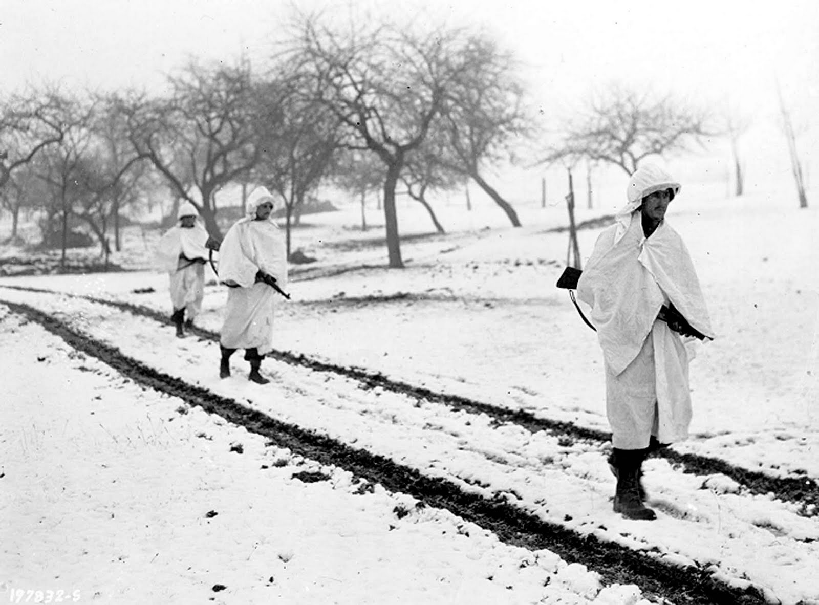 American soldiers traverse over snow-flecked terrain during the Battle of the Bulge. (National Archives)