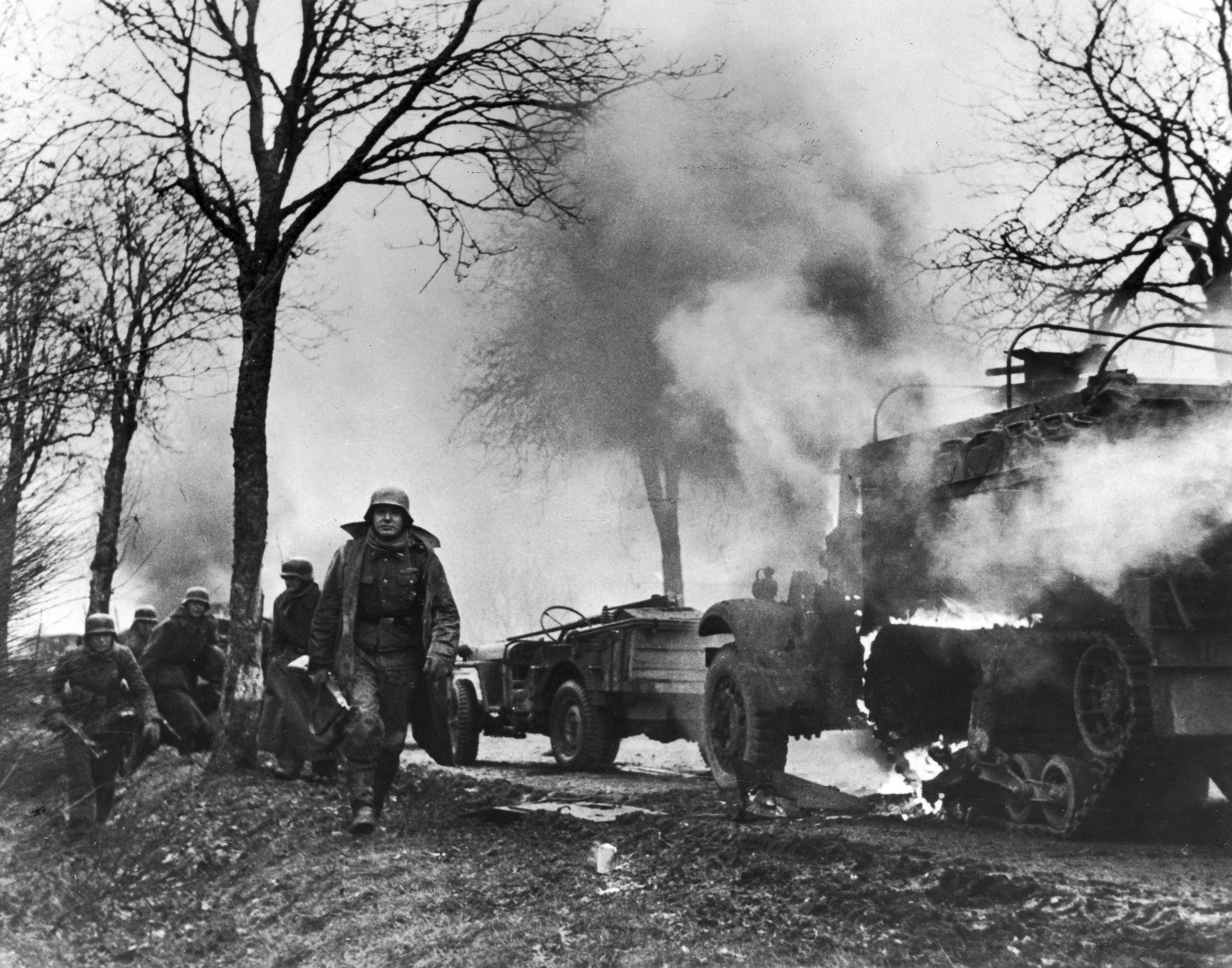German soldiers passing burning American vehicles during the Battle of the Bulge. (National Archives)