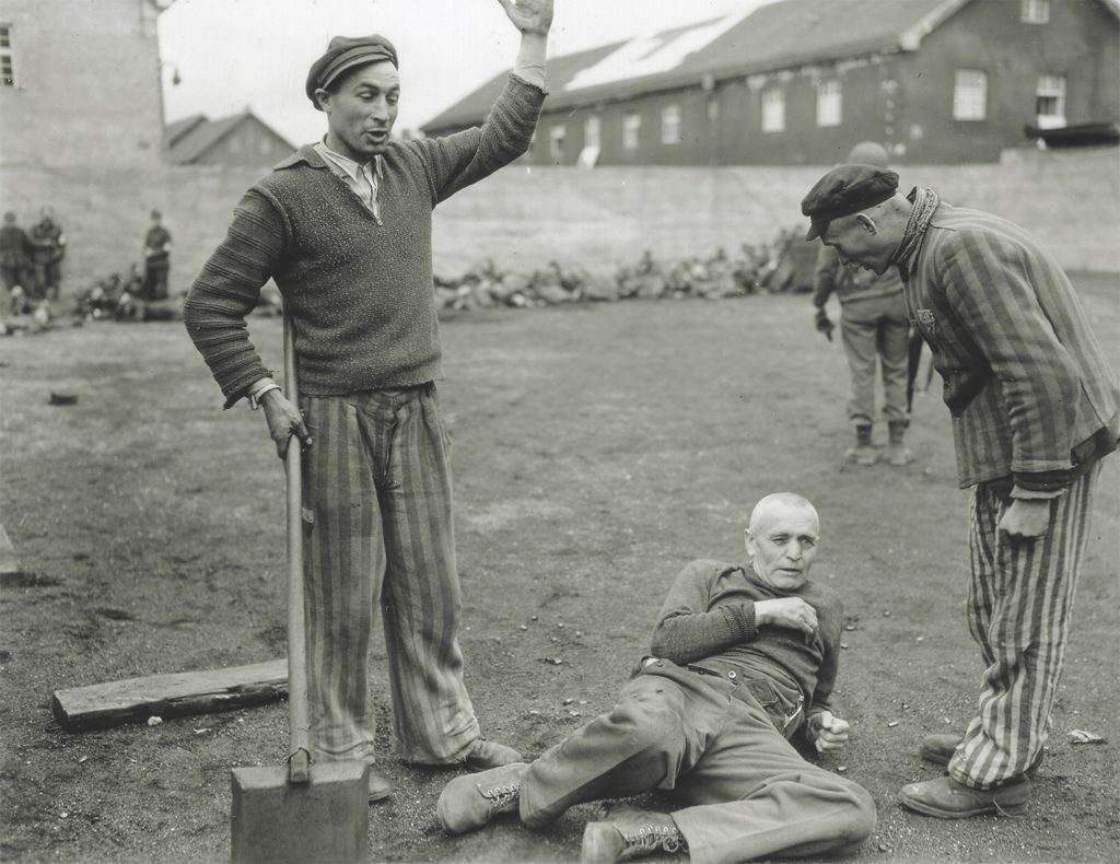 Liberated prisoners beat a camp guard. Soldiers made no move to stop such actions because, as one captain wrote, “THEY SO HAD-IT-COMING.” (National Archives)