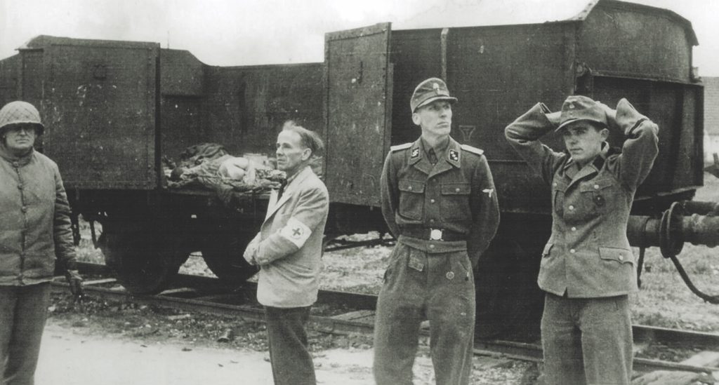 The camp commandant, SS Lt. Heinrich Wicker (second from right), surrendered the camp and its guards to 42nd Division commander Brigadier General Henning Linden (far left, top). Despite the seemingly peaceful transfer, G.I.s reacted with violence at what they saw there. (Hum Images/Alamy)