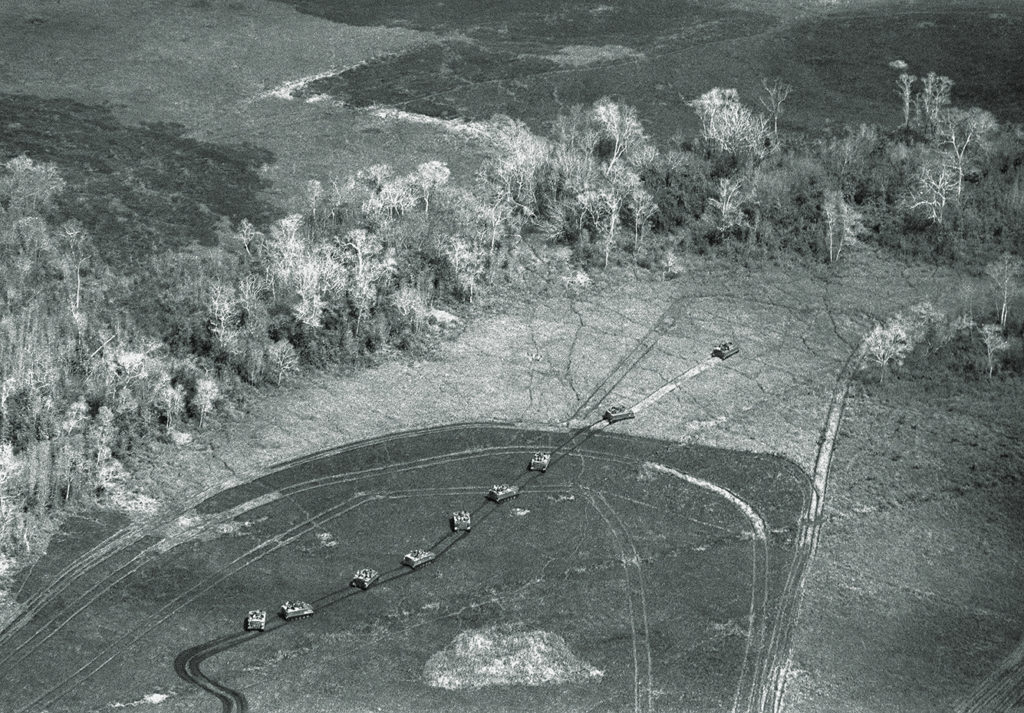Armored cavalry assault vehicles move in file across a swampy jungle clearing in war Zone C, some 20 miles north of Tay Ninh on Feb. 24, 1967. The tracks of other tanks and armored vehicles are already imprinted into the high swamp grass, while infantrymen ring and seal off C zone in a horseshoe like deployment the armor pushes right into the heart of C zone from the south. (AP Photo/Kim Ki Sam)