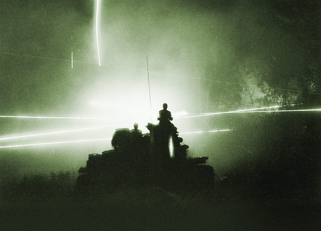 Soldiers of the U.S. 11th Armored Cavalry Regiment are silhouetted atop their tank by the glare of tracer bullets in Cambodia, July 6, 1970. In an exercise known as Mad Minute, they spray the area around them, possibly infiltrated by enemy patrols, before they move on. (AP Photo/Henri Huet)