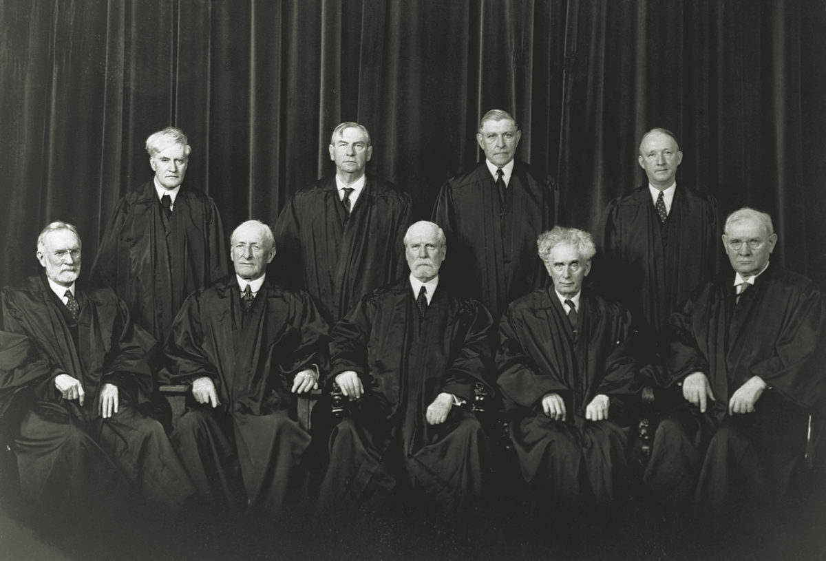 The justices of the Supreme Court. Sitting, from left to right, Justices Sutherland and McReynolds, Chief Justice Hughes, Justices Brandeis and Butler. Standing, left to right, Justices Cardozo, Stone, Roberts, and Black.