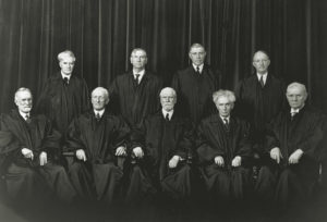 The justices of the Supreme Court. Sitting, from left to right, Justices Sutherland and McReynolds, Chief Justice Hughes, Justices Brandeis and Butler. Standing, left to right, Justices Cardozo, Stone, Roberts, and Black.
