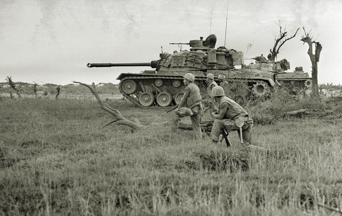 A tank offers support to a group of U.S. Marines awaiting signal to advance on trapped North Vietnamese unit near Da Ha near the DMZ, June 24, 1968. (AP Photo/Dana Stone)