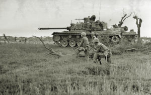 A tank offers support to a group of U.S. Marines awaiting signal to advance on trapped North Vietnamese unit near Da Ha near the DMZ, June 24, 1968. (AP Photo/Dana Stone)