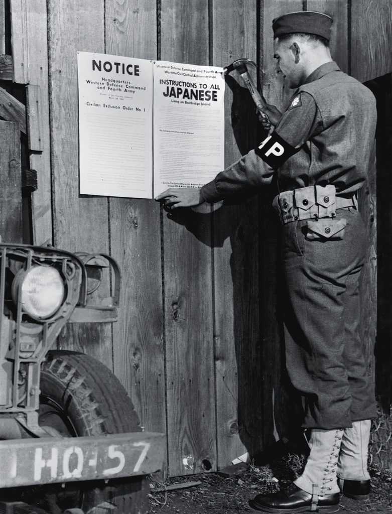 Photo of A military police officer posts Civilian Exclusion Order No. 1, requiring evacuation of Japanese living on Bainbridge Island, Washington, 1942. (Photo by U.S. Army Signal Corps photo./Library of Congress/Corbis/VCG via Getty Images)