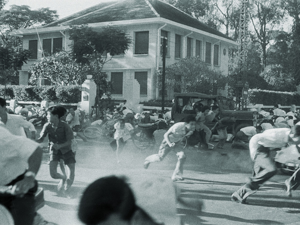 Photo of South Vietnam: Failed Coup In Saigon Against President Ngo Dinh Diem. Saigon- 17 novembre 1960- Lors du coup d'état manqué contre le président NGO DINH DIEM, des jeunes gens (révolutionnaires) accourent dans une rue, lâchant leur bicyclette pour se protéger de coups de feu, un camion militaire derrièer eux dans une rue, une demeure en arrière-plan.