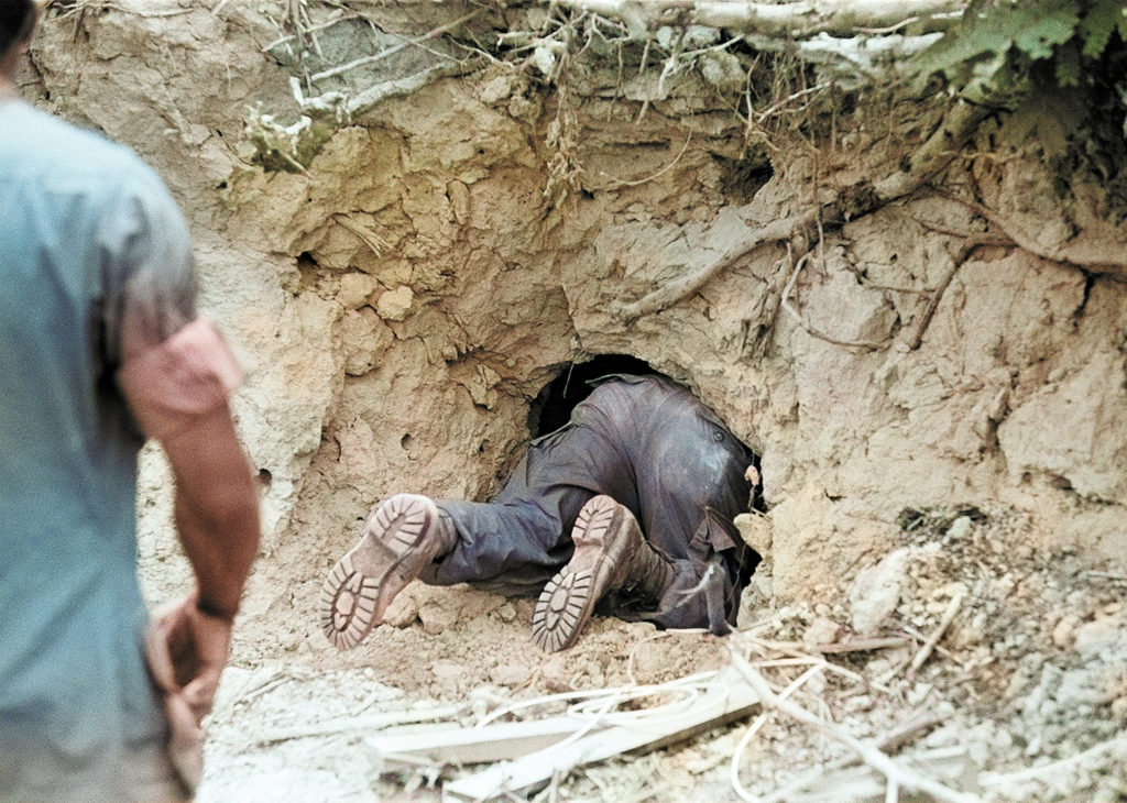 Photo of Trooper attached to a mechanized unit of the U.S. 25th division slowly crawls into Viet Cong tunnel in a weep through the Ho Bo woods north of Saigon, March 18, 1968. This was part of the largest allied offensive of the war, Operation “Quyet Thang” (resolved to win), with some 50,000 men sweeping through the five provinces around the capital City of Saigon. Their objective is to sweep out the remnants of Vietcong units who attacked the city in force during the Tet offensive. This “tunnel rat” as he is called, is a volunteer who checks out tunnels after initial grenades or smoke attacks. In this tunnel nothing was found.