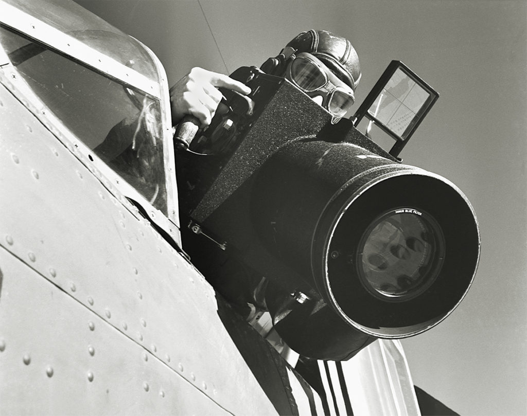 Photo of a U. S. Navy photographer readies his reconnaissance camera for a shot from an airplane. Norfolk Naval Air Station, Virginia. | Location: Norfolk Naval Air Station, Norfolk, Virginia, USA.
