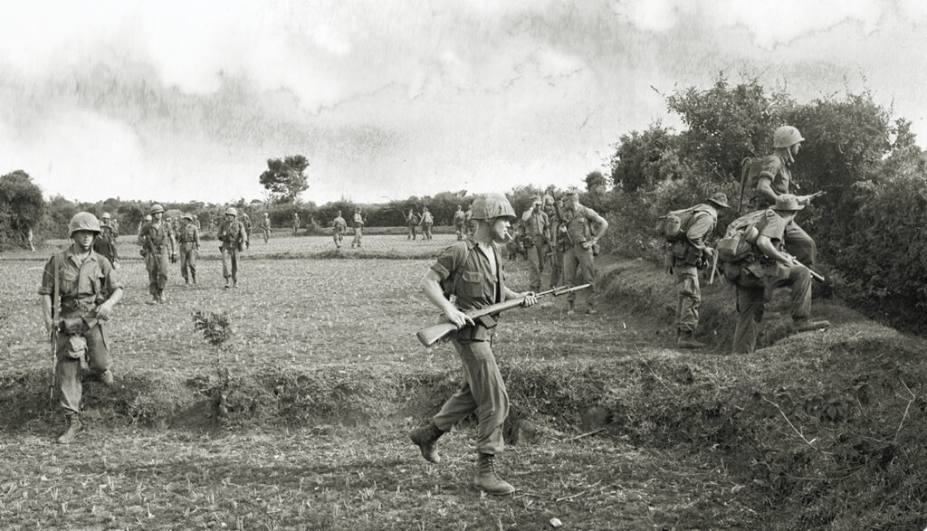 Photo of Men of Company E, 2nd Battalion, 4th Marines move out from LZ White during Operation Starlite. A fierce fight soon arose with VC entrenched to the right.