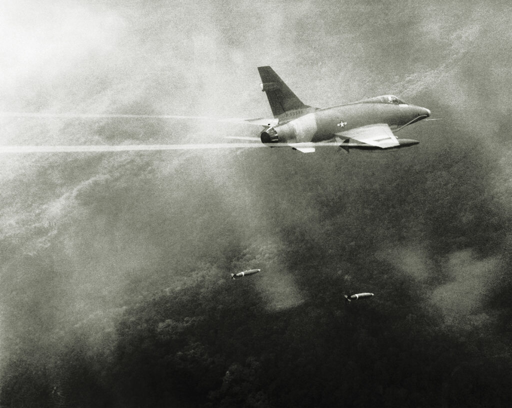 Photo of a U.S. Air Force F-100 Super Sabre jet drops its bombs on an enemy position near the Do Duc outpost, some 90 miles north of Saigon, during a mission in the Vietnam War.