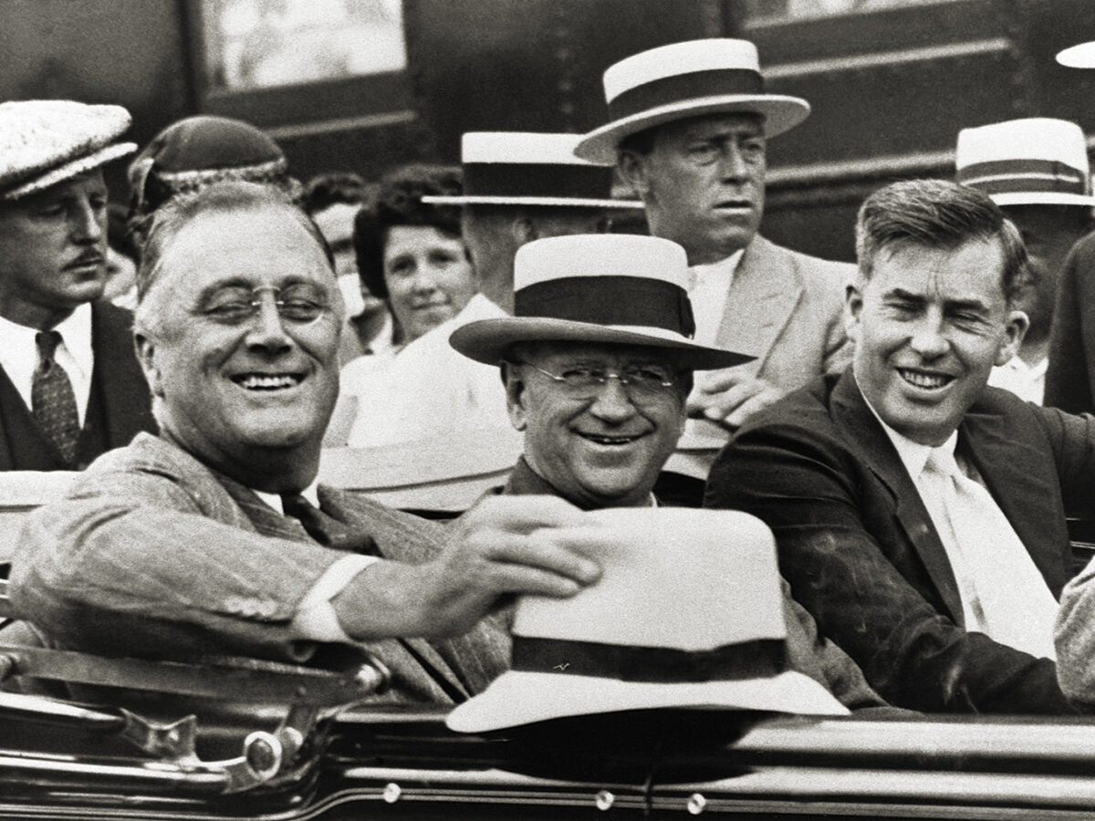 Photo of US President Franklin D. Roosevelt (left) rides in an automobile with Secretary of the Interior Harold L. Ickes (center), and Secretary of Agriculture Henry A. Wallace (right). The photo was taken in August of 1933, at the beginning of the New Deal administration.