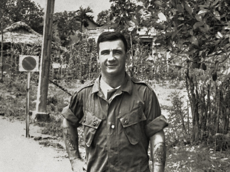 Photo of Warrant Officer Class II, (WO2), Kevin (Dasher) Arthur Wheatley VC, a member of the Australian Army Training Team, Vietnam, (AATTV) standing on the roadside near Saigon. WO2 Wheatley was awarded a Victoria Cross (VC) posthumously for action against the Viet Cong. He moved a wounded soldier, WO2 R. J. Swanton, from the open paddy fields into a wooded area and remained with him knowing the Viet Cong were moving in on their position.