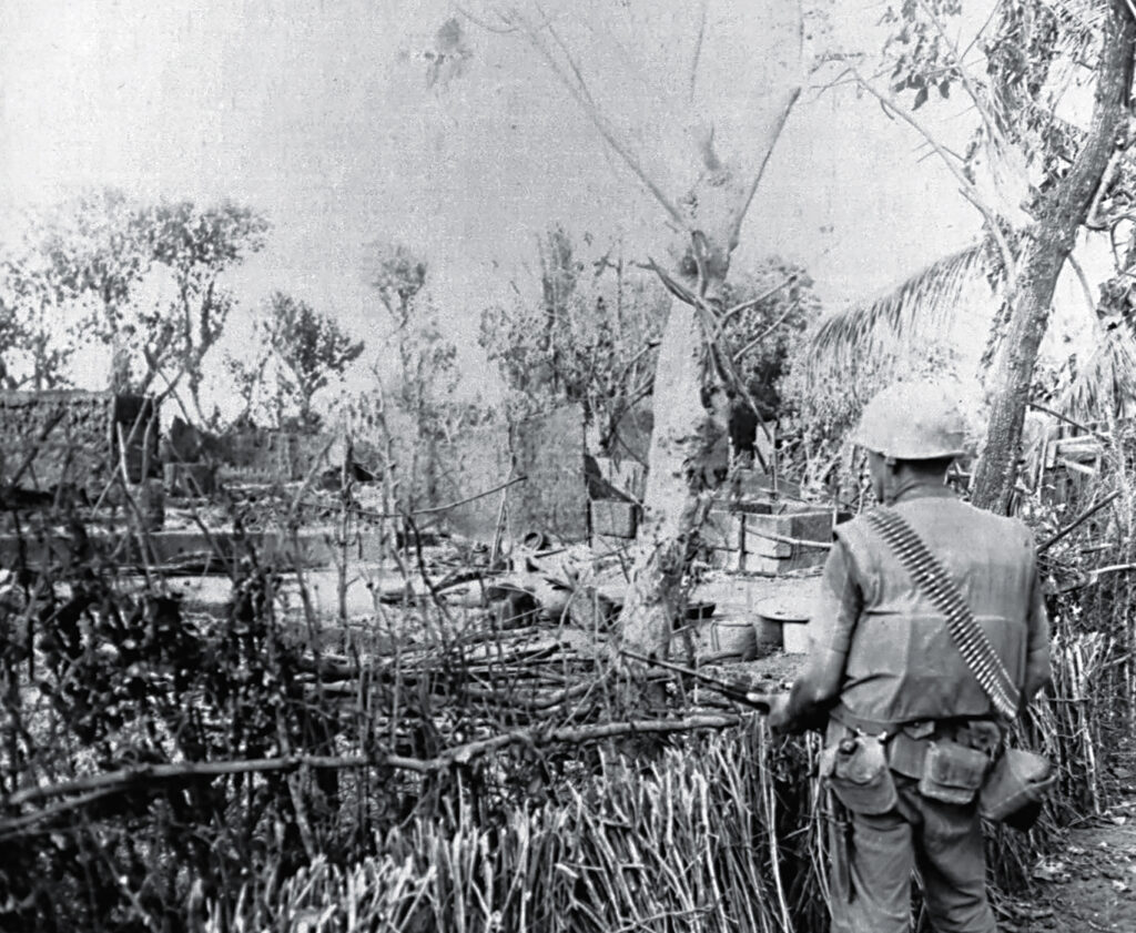 Photo of a Marine rifleman surveying the damage left in the aftermath of a U.S. airstrike on a Viet Cong village on the Van Tuong peninsula on Aug. 22, 1965, during Operation Starlite. The VC made skillful use of harsh terrain to camouflage their well-fortified positions.