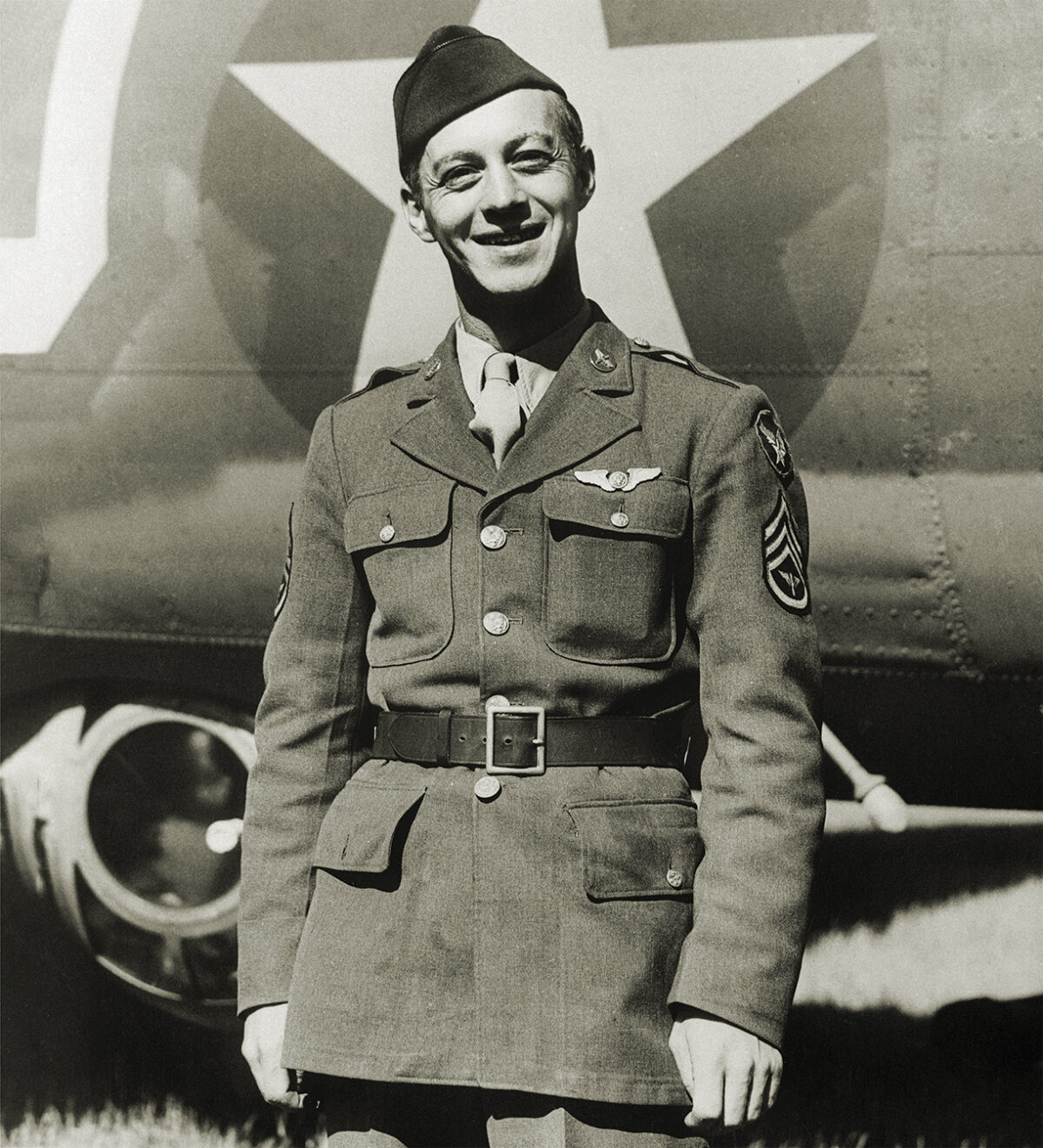 Photo of Staff Sergeant Maynard H. smith, of Caro, Michigan, is the first enlisted man in the European Theater of operations to be recommended for the Congressional Medal of honor. his amazing cool-headedness and bravery after a Flying Fortress raid on St. Nazaire earns him that honor. with three members of the crew baled out, Sergeant Smith managed to administer aid to the wounded tail gunner, blast at Nazis from the two waist guns, and fight fire and removing popping ammunition all at once. Sergeant smith was tail gunner and completely cut off from the pilot and co-pilot. his fire fighting and first aide action saved his ship and the lives of all aboard.