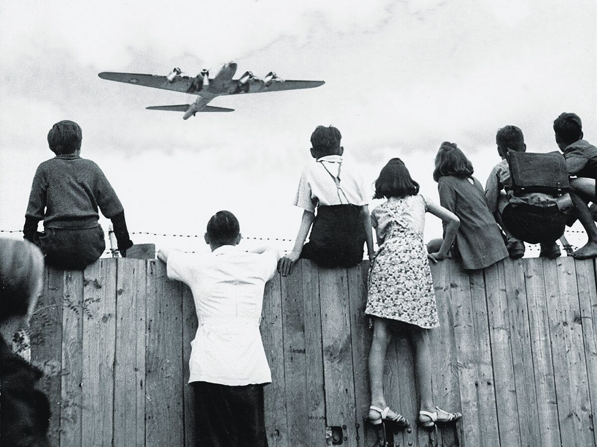 Photo of West Berlin children perched on the fence of Tempelhof airport watch the fleets of U.S. airplanes bringing in supplies in 1948 to circumvent the Russian blockade of land and waterways. The airlift began June 25, 1948 and continued for 11 months.