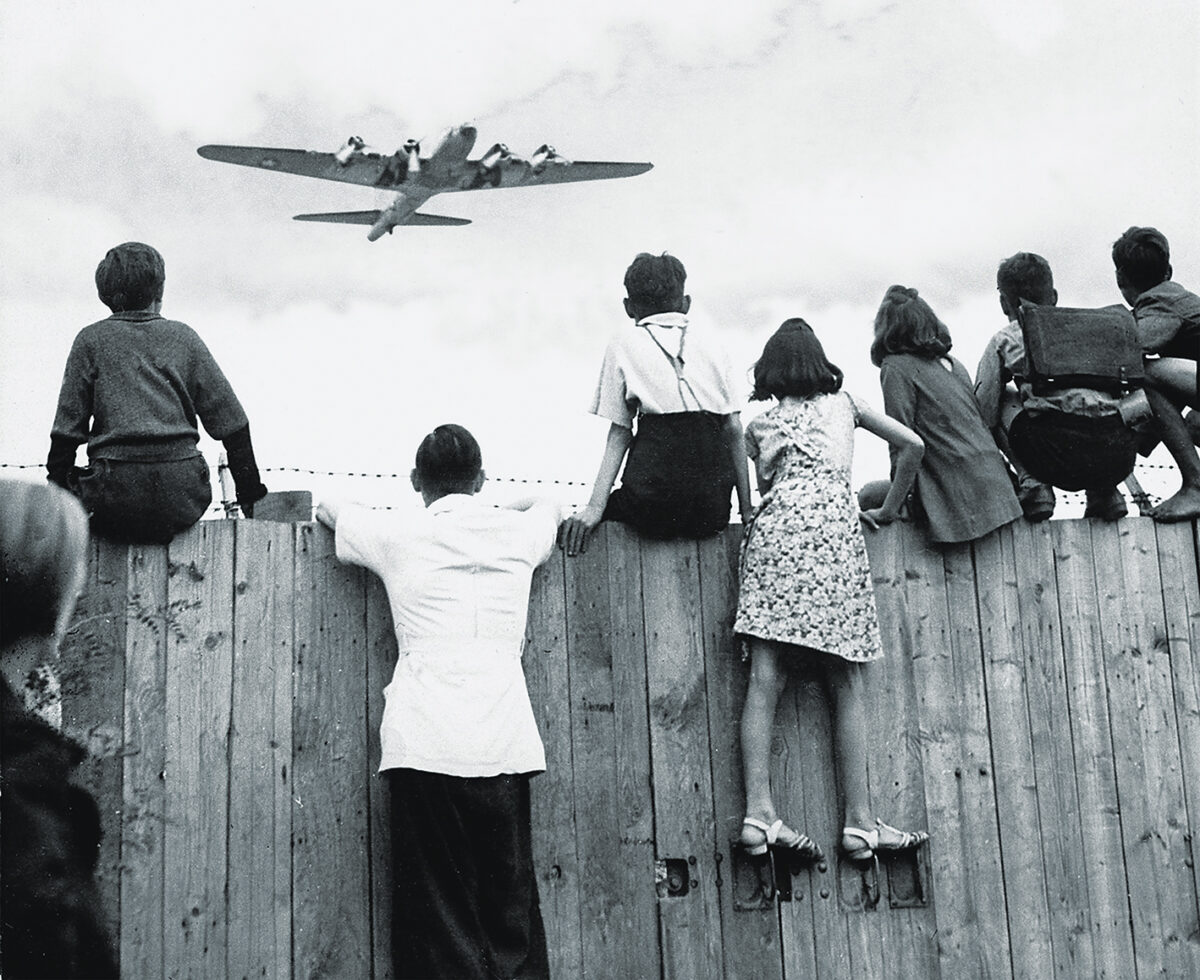 Photo of West Berlin children perched on the fence of Tempelhof airport watch the fleets of U.S. airplanes bringing in supplies in 1948 to circumvent the Russian blockade of land and waterways. The airlift began June 25, 1948 and continued for 11 months.