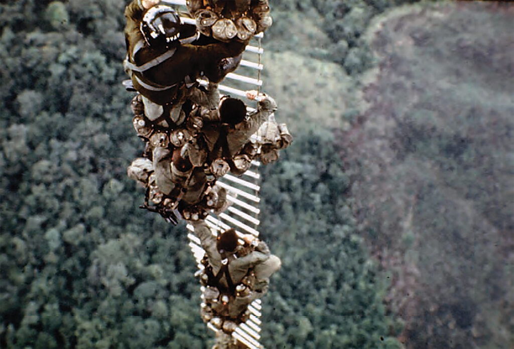 Photo of a reconnaissance team led by Sgt. Gerald Plank ascends to safety from a “hot area” in Laos. Retractable aluminum ladders were used both to insert and extract SOG units. Men extracted from enemy territory were often too tired to climb all the way up the ladders and hung from them across long distances while being flown to safety.