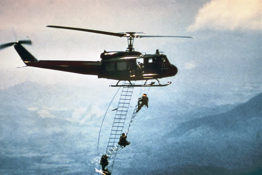 Photo of Members of an SOG reconnaissance team from Command and Control Central (CCC) based in Kontum, South Vietnam, scale retractable ladders in midair during an emergency extraction from Laos. Rapid extractions saved many SOG men who were being threatened by enemy forces.