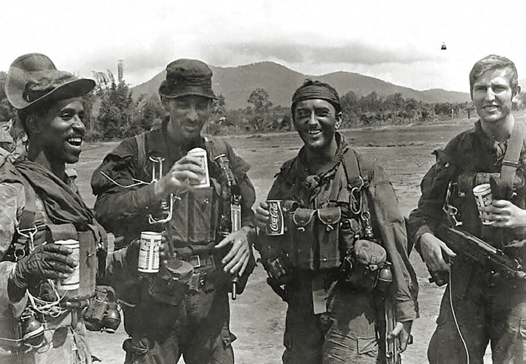 Photo of SOG men smiling as they celebrate the success of a hazardous full-length mission involving a HALO jump; the troopers successfully landed together without sustaining any injuries and accomplished their objectives. They are, from left to right: Willard Moye, Capt. Jim Storter, Newman Ruff, and Michael Bentley.