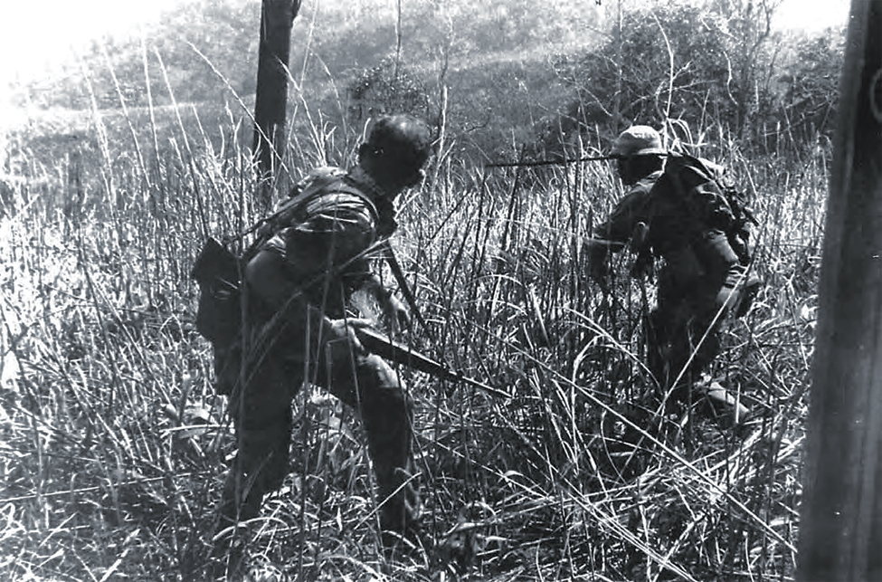 Photo of SOG men (Sgt. Maj. Billy Waugh, left, and Sfc. Melvin Hill) duck from incoming fire from NVA soldiers after getting off a helicopter about 22 kilometers north of Khe Sanh.