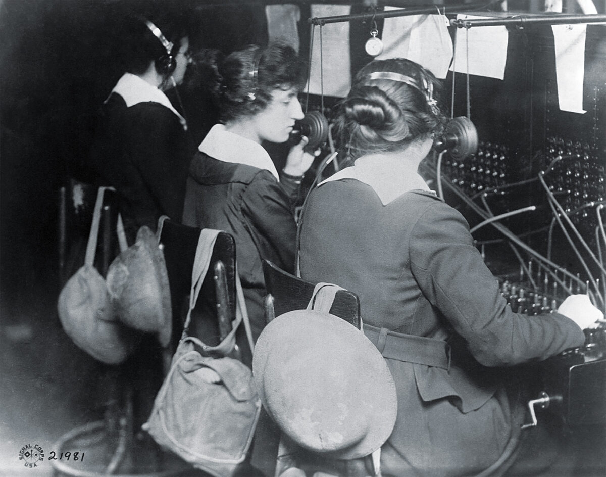 Photo of Telephone operators working with the U.S. Signal Corps work at a switchboard in American military headquarters at St.-Mihiel, France. Gas masks and helmets hang at the ready in case of German shelling or gas attacks. Their efficiency and bravery contributed greatly to the effort to capture St.-Mihiel.