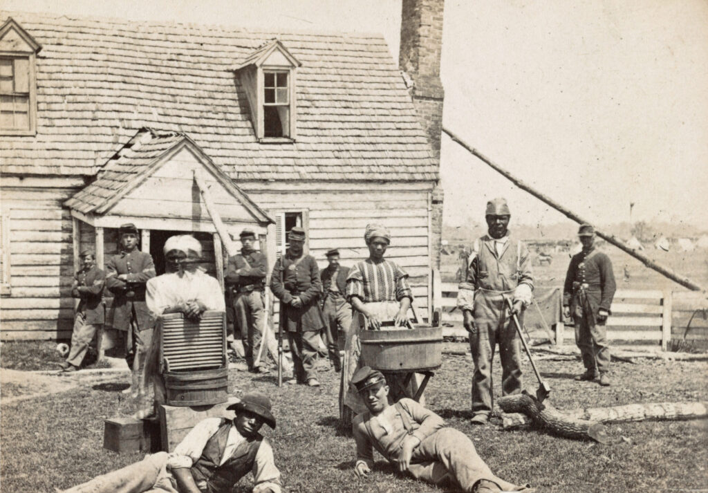 Black refugees with Union troops outside a house