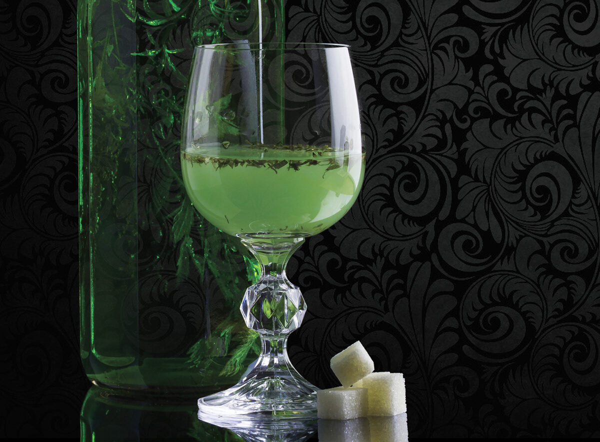 Photo of a glass and bottle of absinthe with sugar cubes.