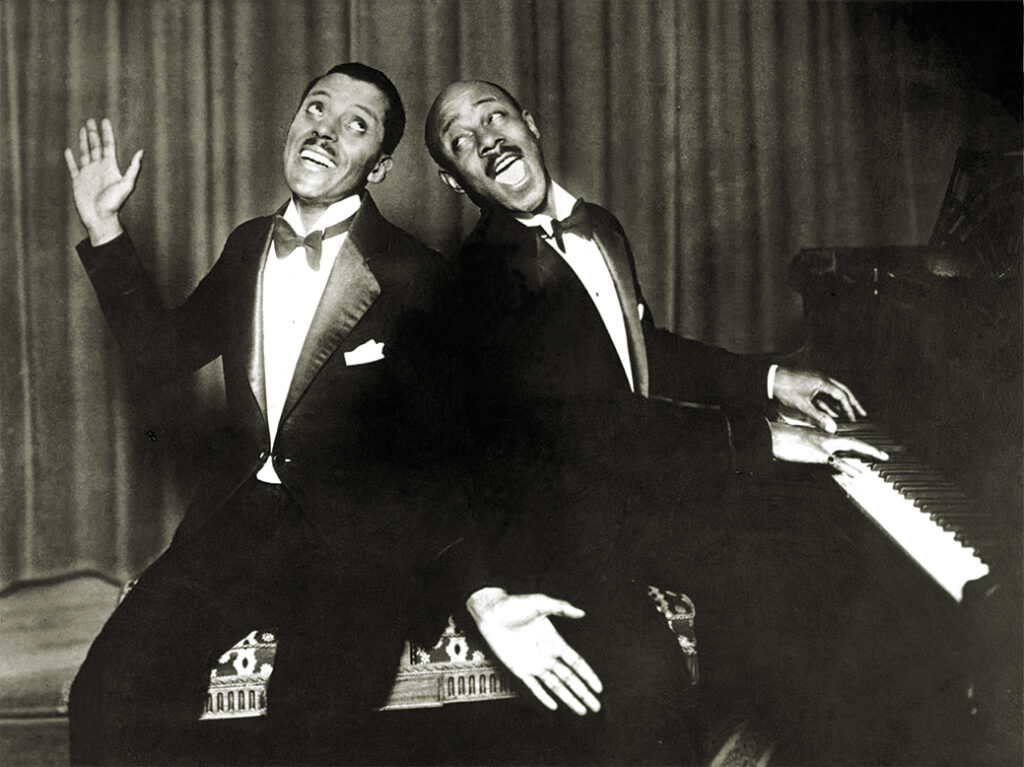 Photo of Noble Sissle and Eubie Blake posing at the piano in the early 1920s.