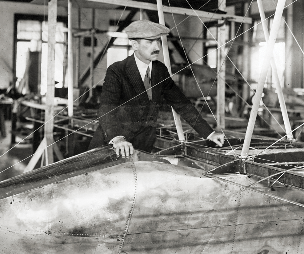 Photo of Glenn Curtiss: (1878-1930) Pioneer of American aviation in his workshop examining new type of biplane flying boat glider.