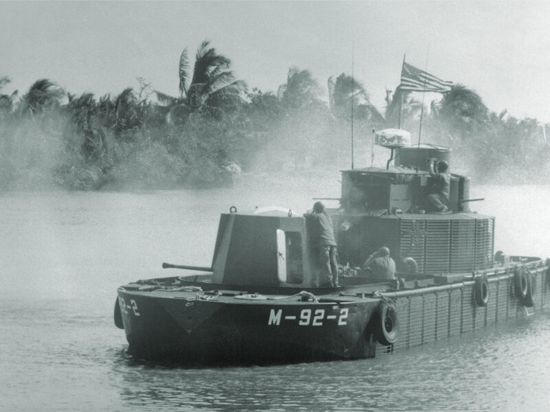 Photo of Crewmen on board the Monitor, a "battleship" of the U. S. Navy's River Assault Force, fires 40 mm shells toward enemy positions in a jungle during recent operations in the Mekong Delta. The concept of riverine operations dates back to the U. S. Civil War and was used to divide the South in that conflict. In Vietnam, the Monitor is part of a flotilla which provides support to U. S. ground combat troops.