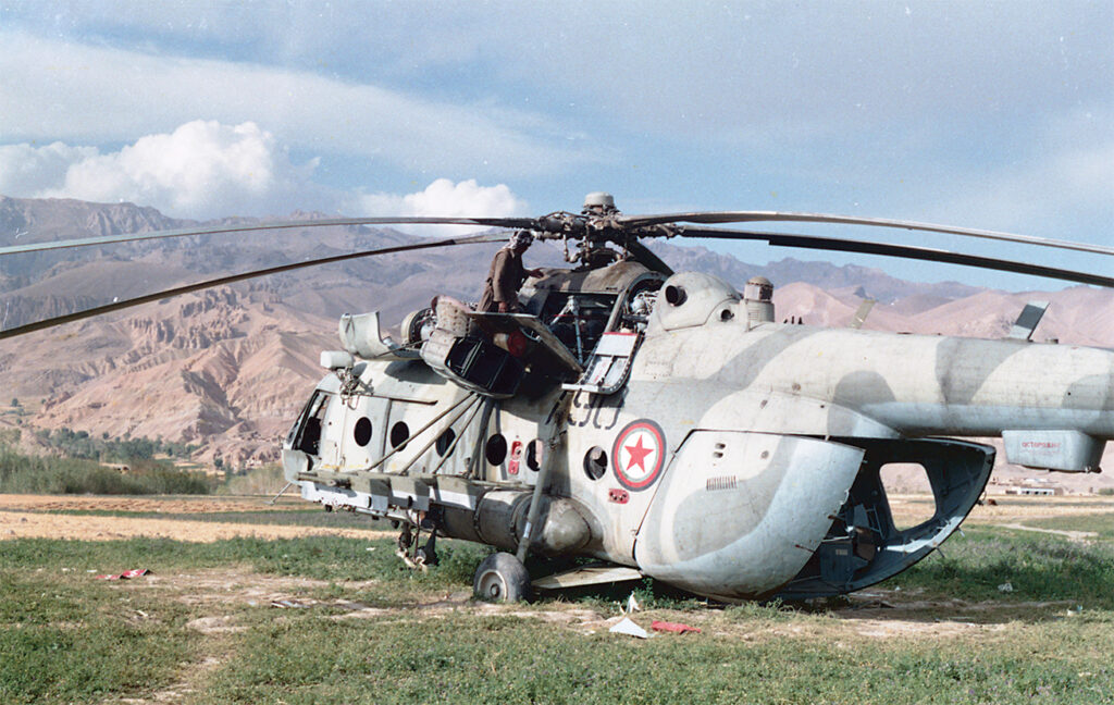 Photo of a Mujahideen inspecting the hulk of a disabled Mil Mi-8.