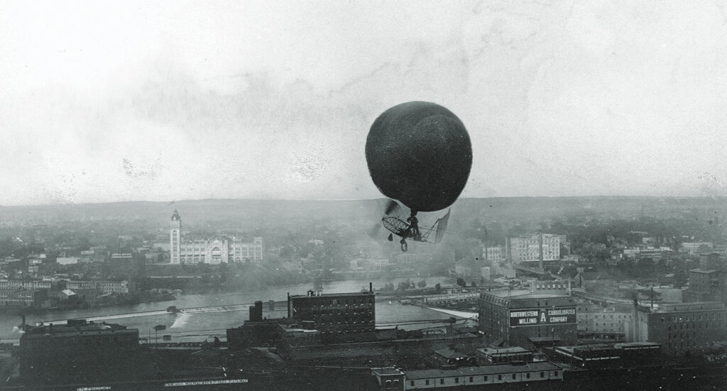 Photo of Roy Knabenshue fling the first lighter-than-air craft over the buildings of Minneapolis in 1907.
